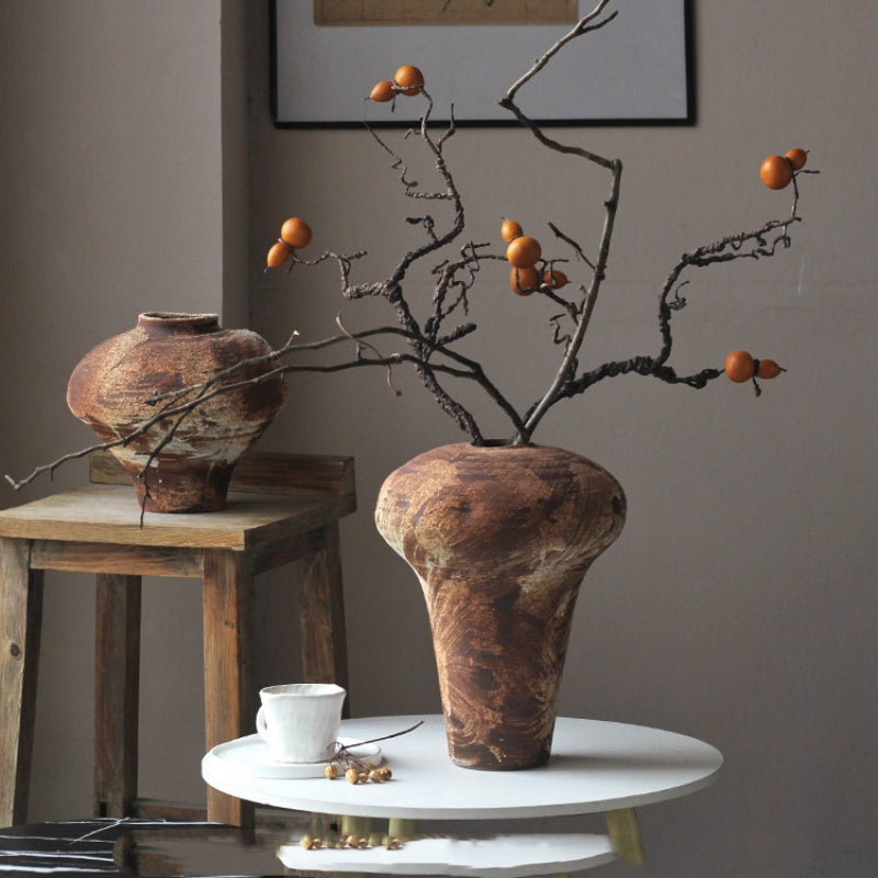 Rustic ceramic vase with dried branches on side table