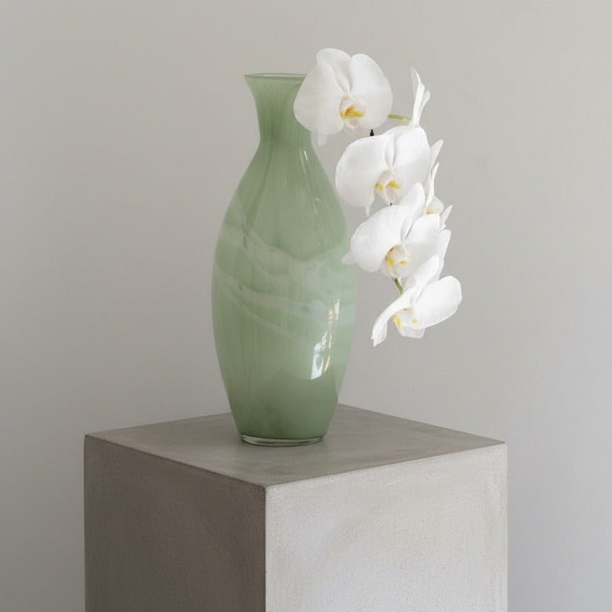 Large sage green glass bottle vase styled with white orchids