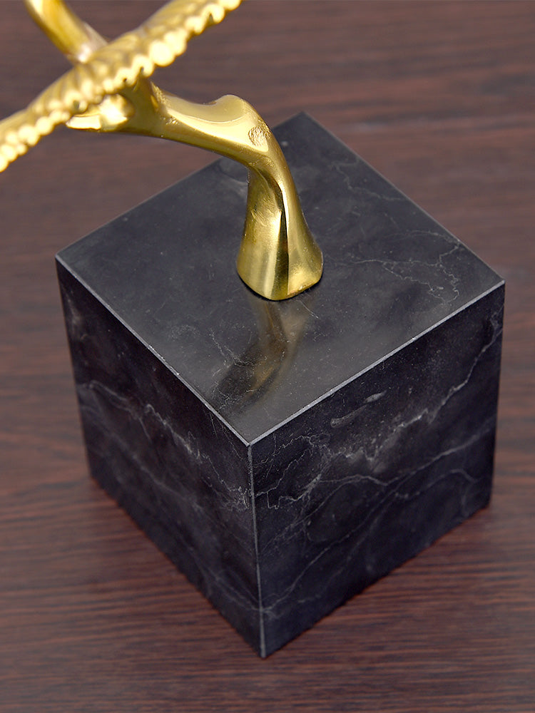 Close up detail of solid black marble cube base with brass trunk connection