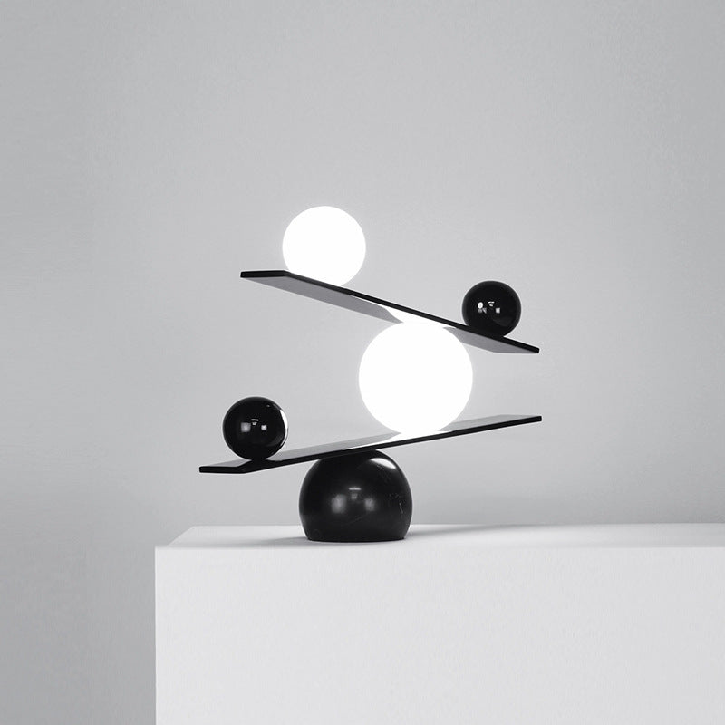 Illuminated opal glass orb balancing on black beam modern lamp design