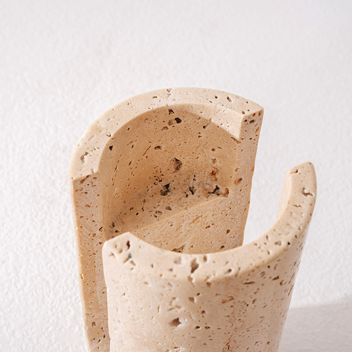 Top-down view of the U-shaped cutouts and hollow interior of the raw travertine candle stand