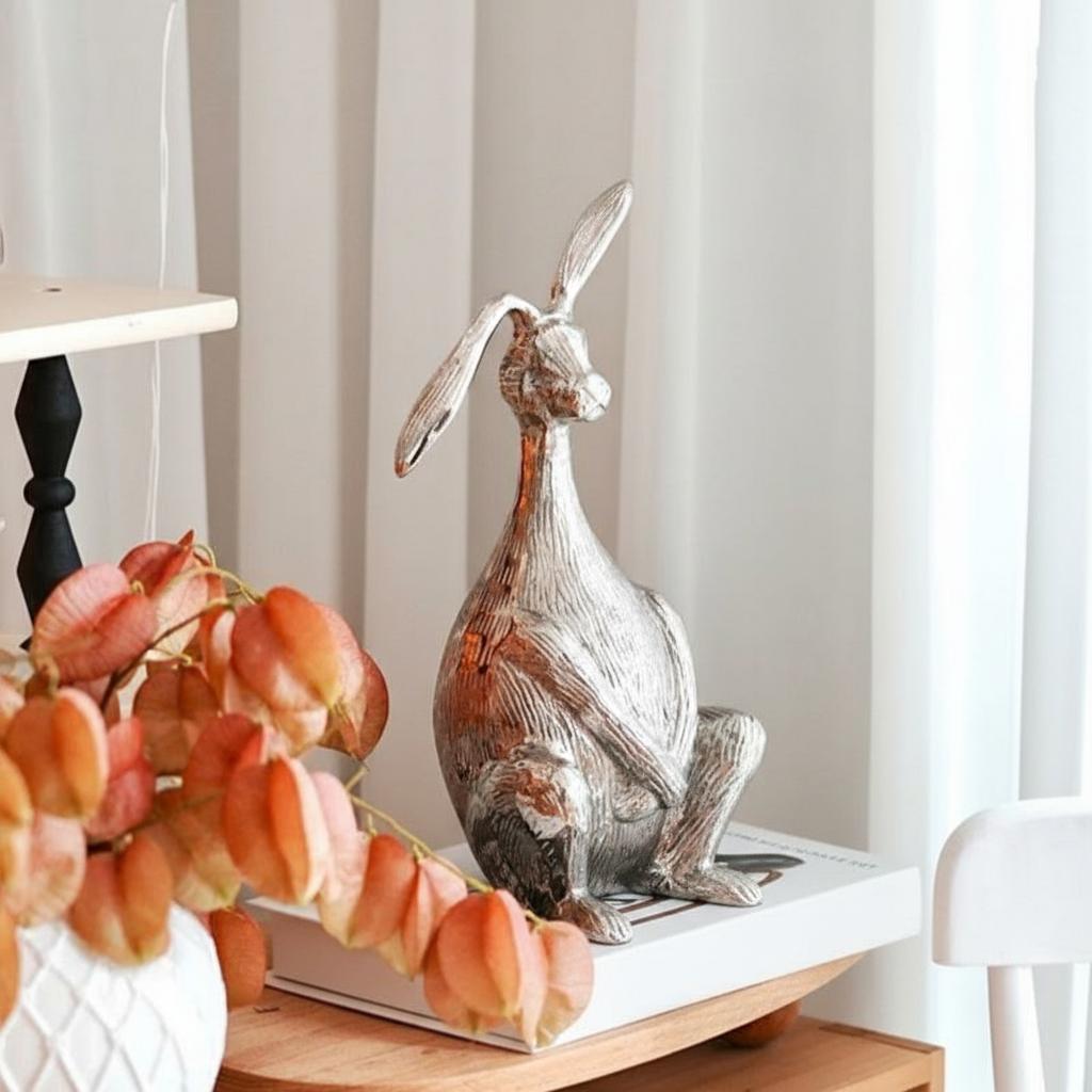 Front view of silver aluminum hare sculpture on book