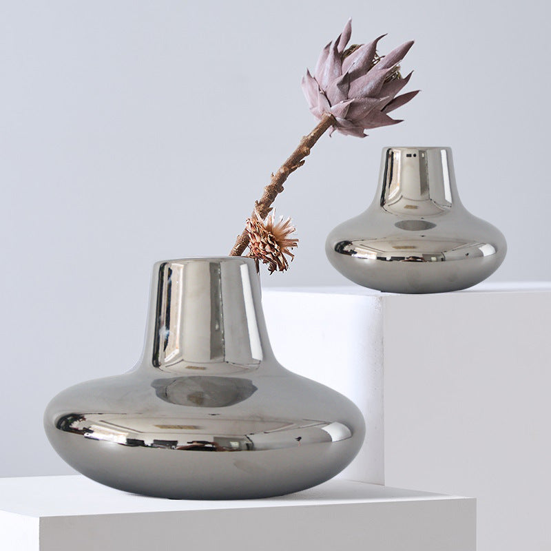 Lifestyle display of silver chrome vases on white plinths