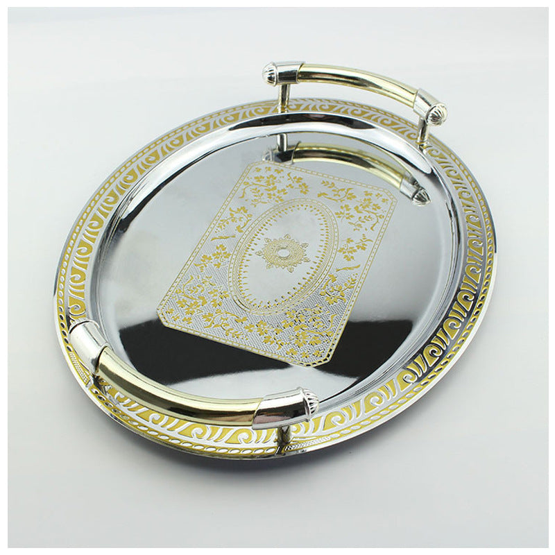Angled perspective of reflective silver platter with gold scrollwork border