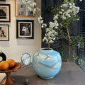 Sky blue ceramic round vase with flying crane motif on table