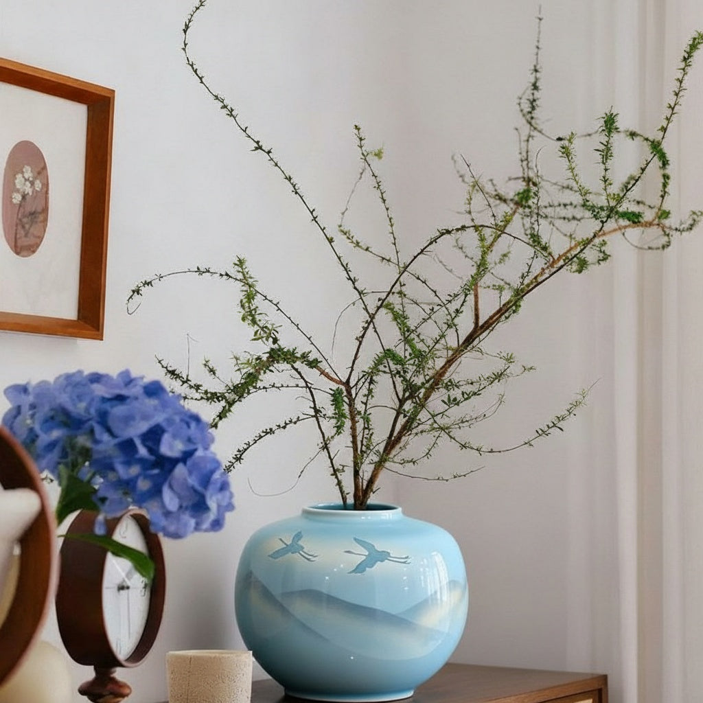 Blue ceramic vase with crane art styled with greenery