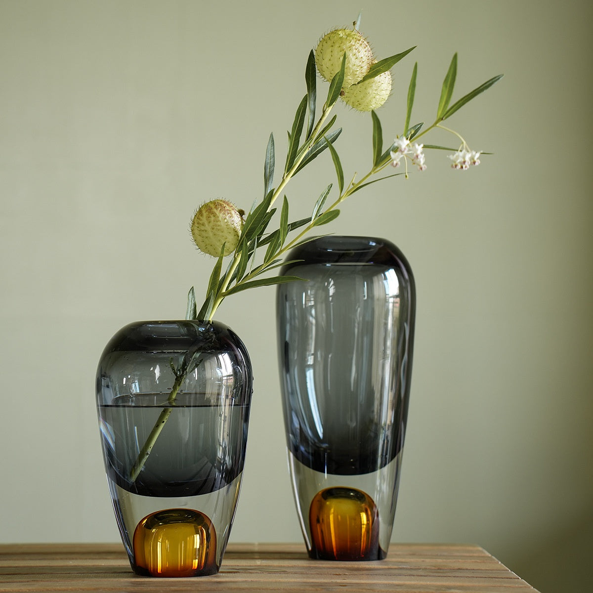 Two toned glass vases with flowers on wooden table