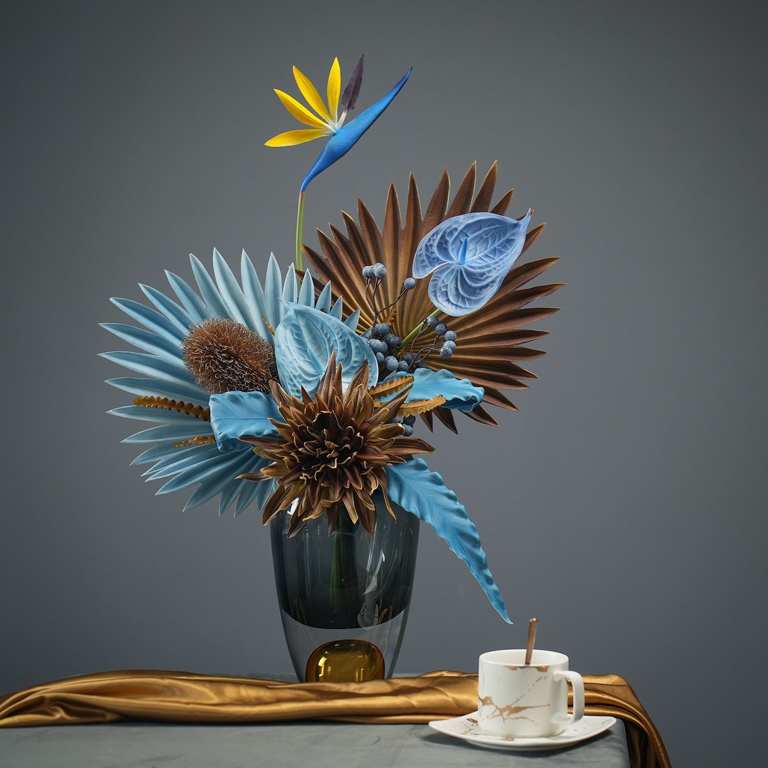 Smoke grey vase with solid amber base holding blue flowers