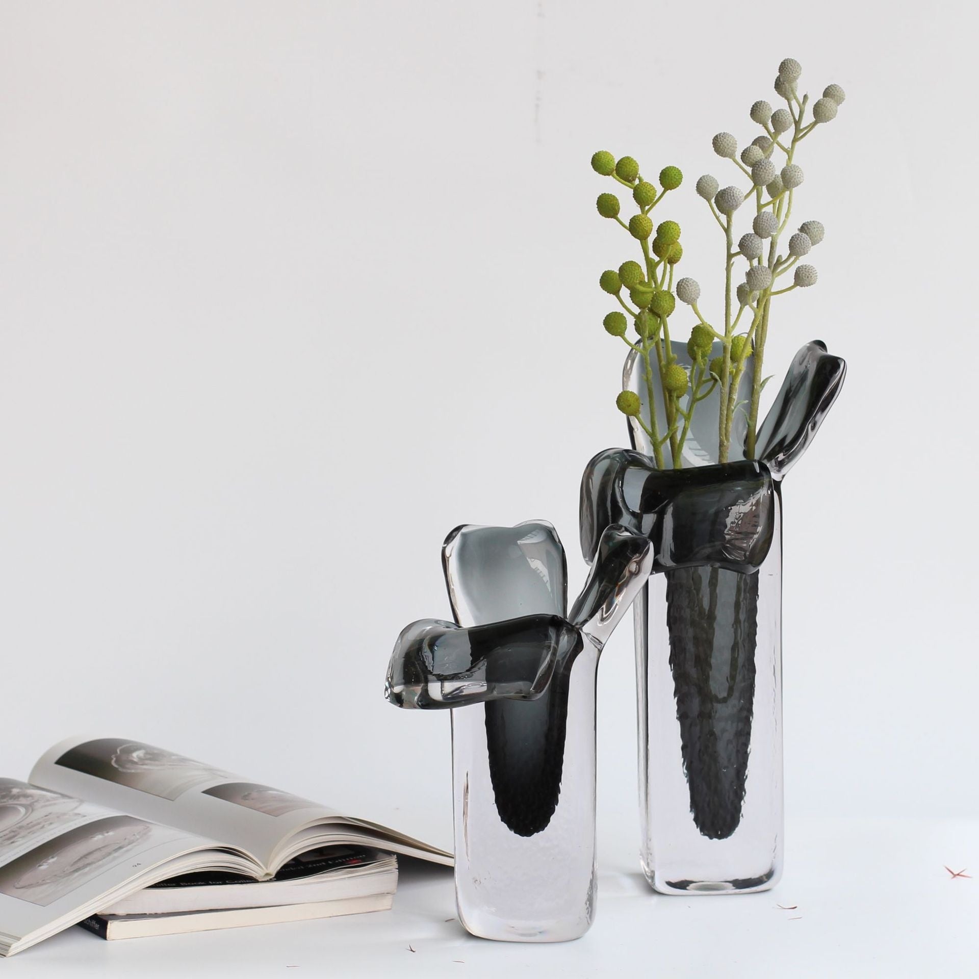Two smoke grey art glass vases with organic rims styled with greenery