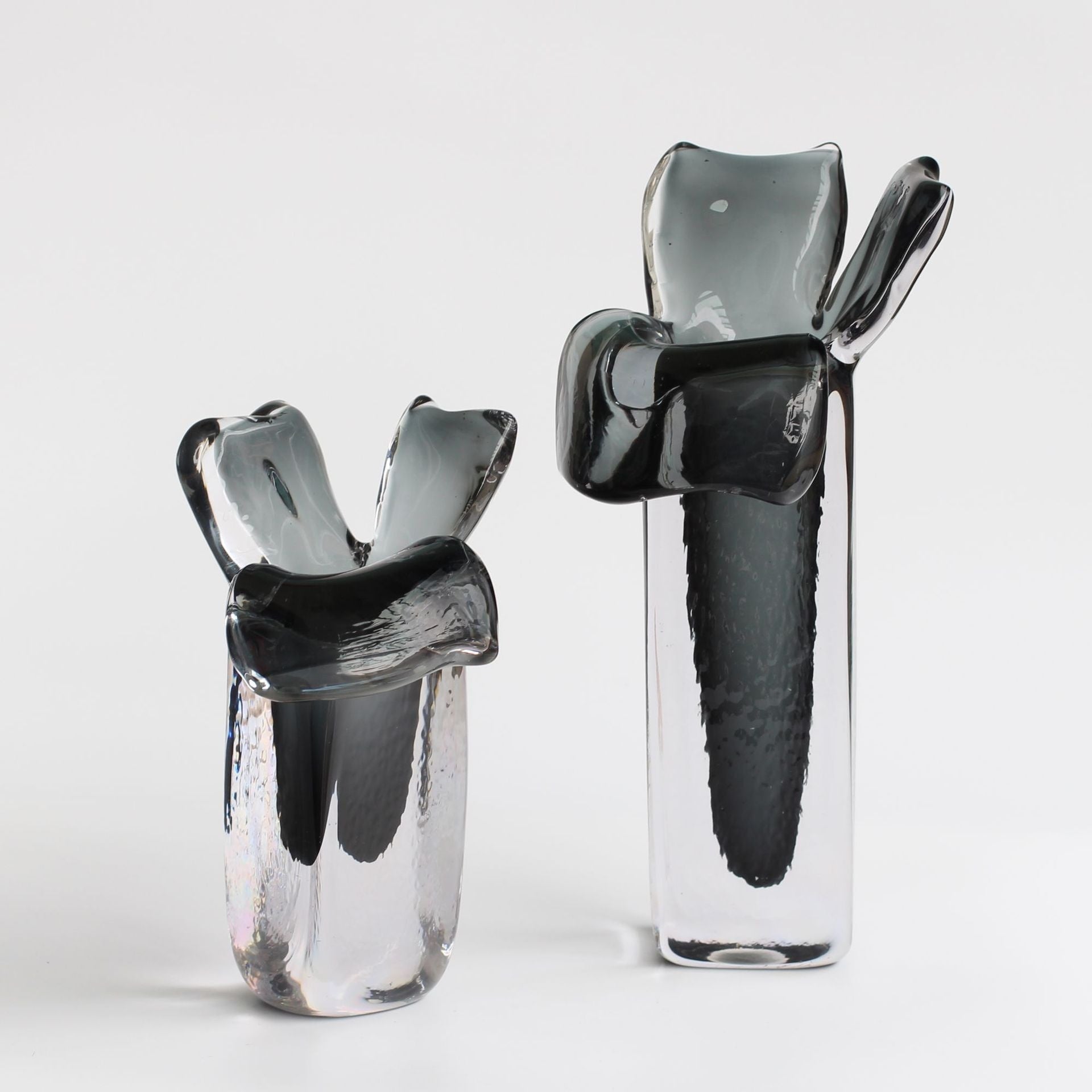 Set of two sculptural glass vases with flared rims on white background