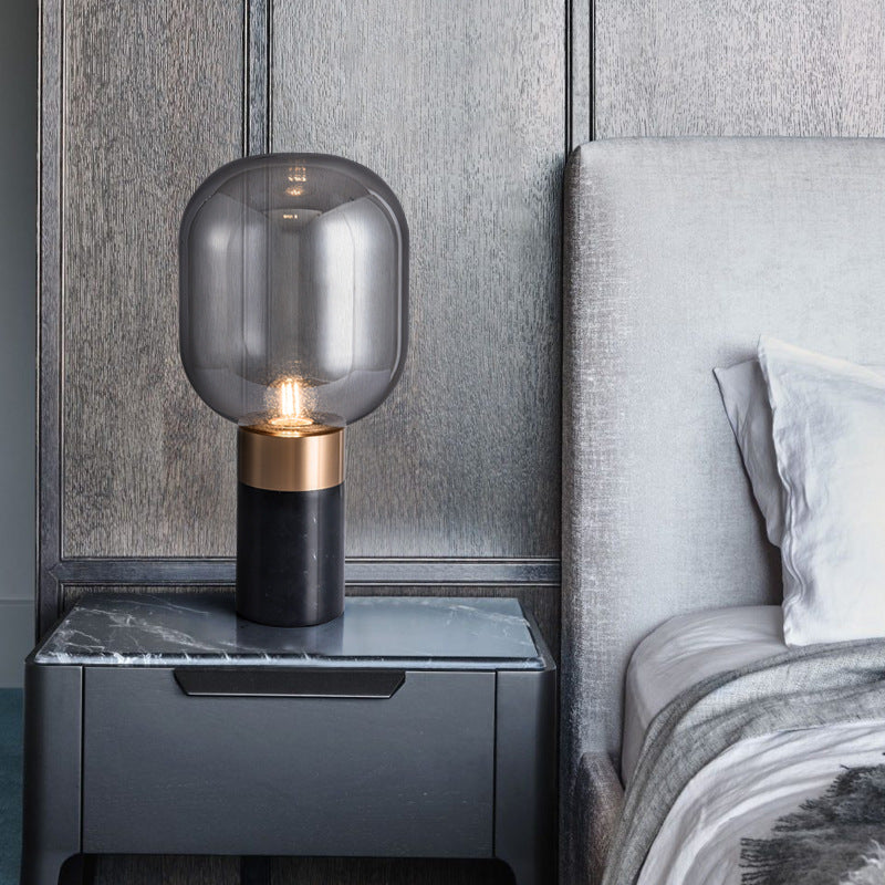Modern smoke grey glass lamp with black marble base styled in a dark luxury bedroom interior