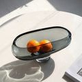 Smoke grey glass fruit bowl holding oranges in sunlight