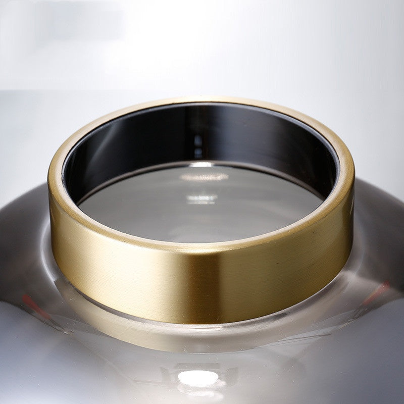 Detail shot of brushed gold rim on smoked glass vase