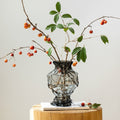 Smoked glass sculptural vase displaying fresh botanical branches