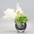 Smoked glass round vase with green hydrangea and white pampas arrangement