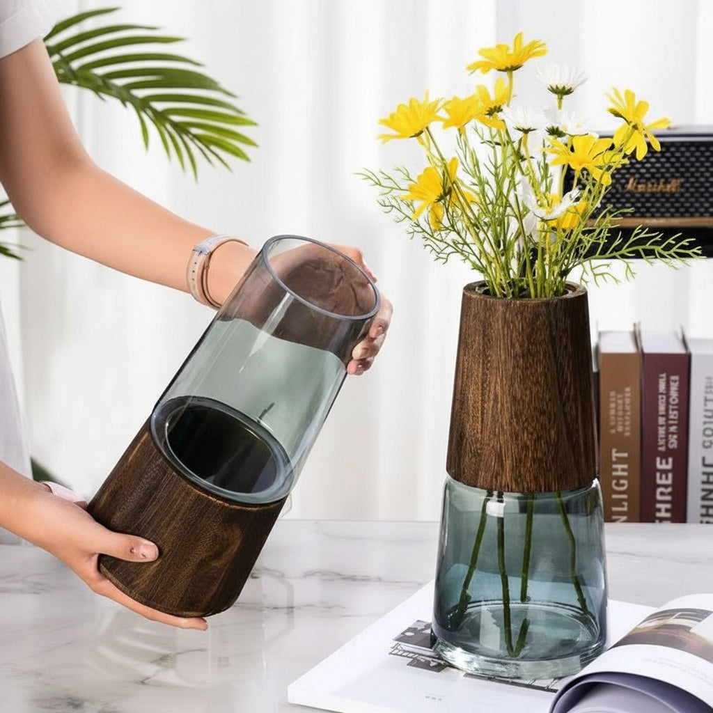 Smoked glass vase with dark wood base holding flowers