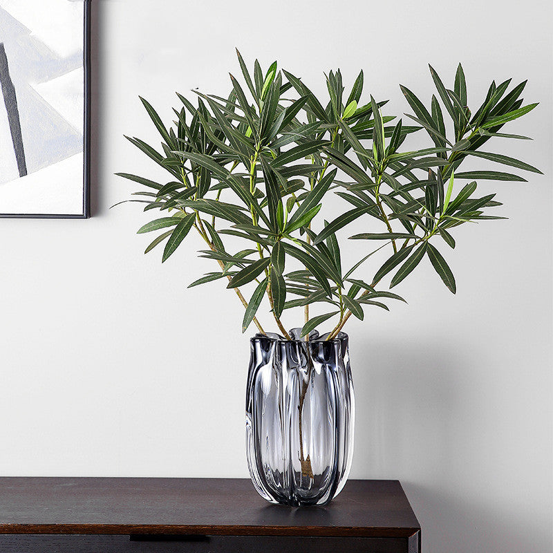 Large smoked grey glass vase with greenery on console