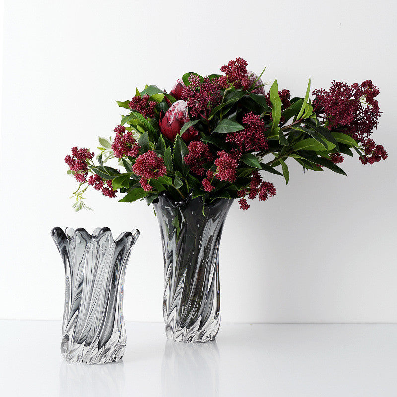 Two smoked grey glass vases with red floral arrangements