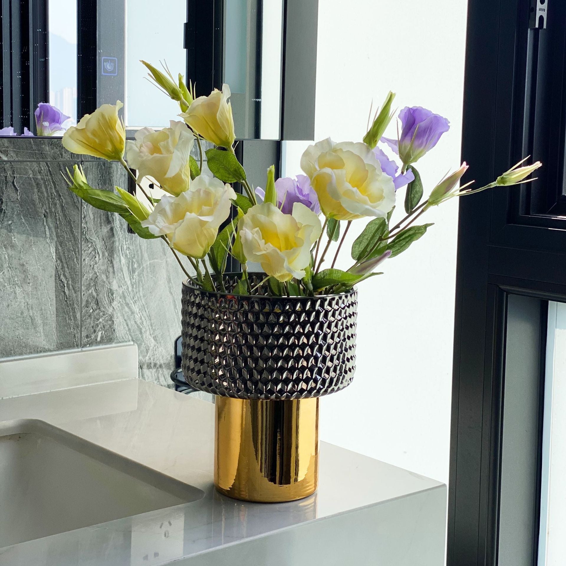 Medium smoky glass vase with gold base holding white flowers