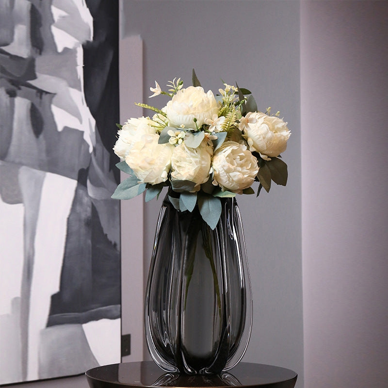 Tall smoky grey glass vase with white flowers on table