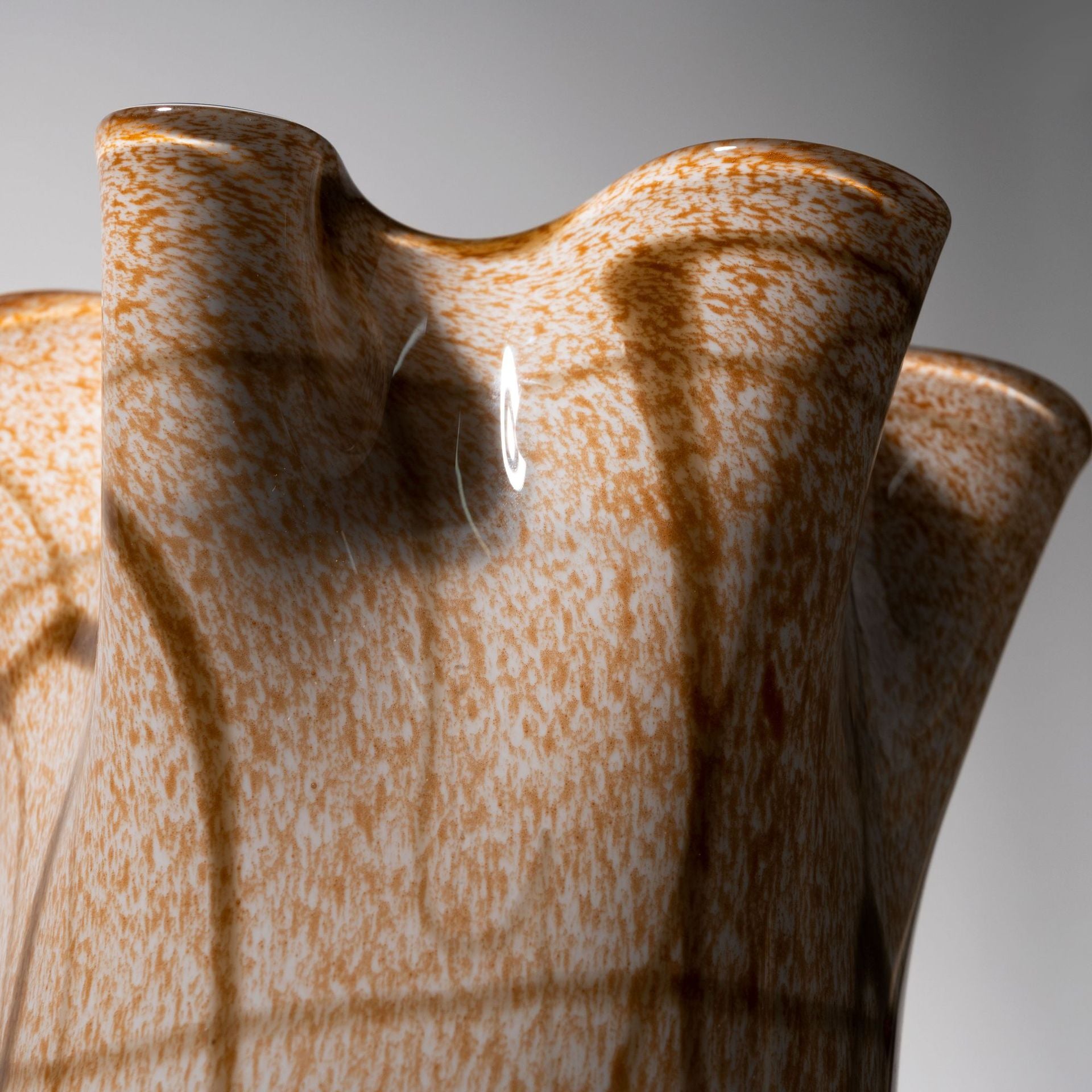 Close up detail of speckled texture and ruffled glass rim