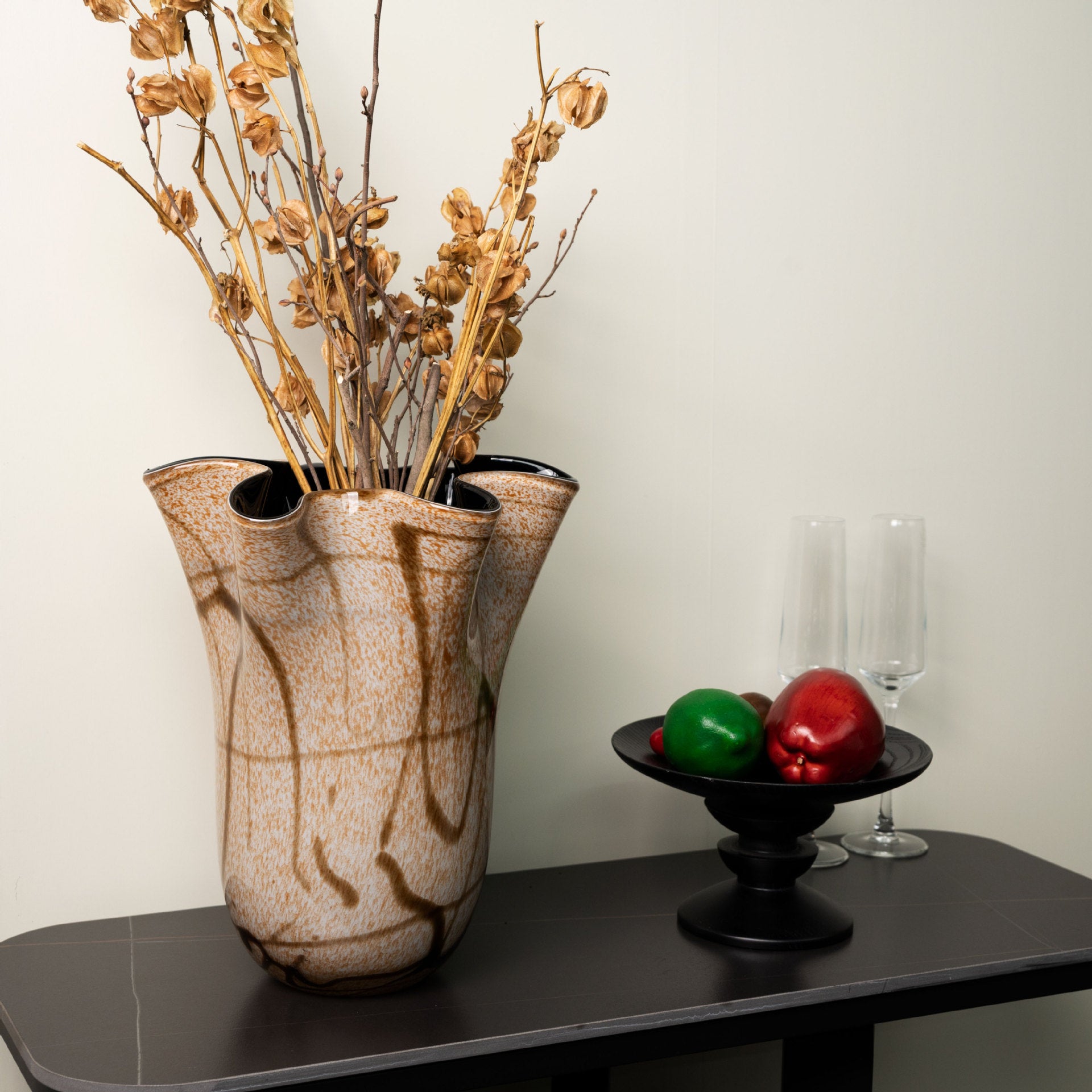 Amber art glass vase with dried flowers on dark table