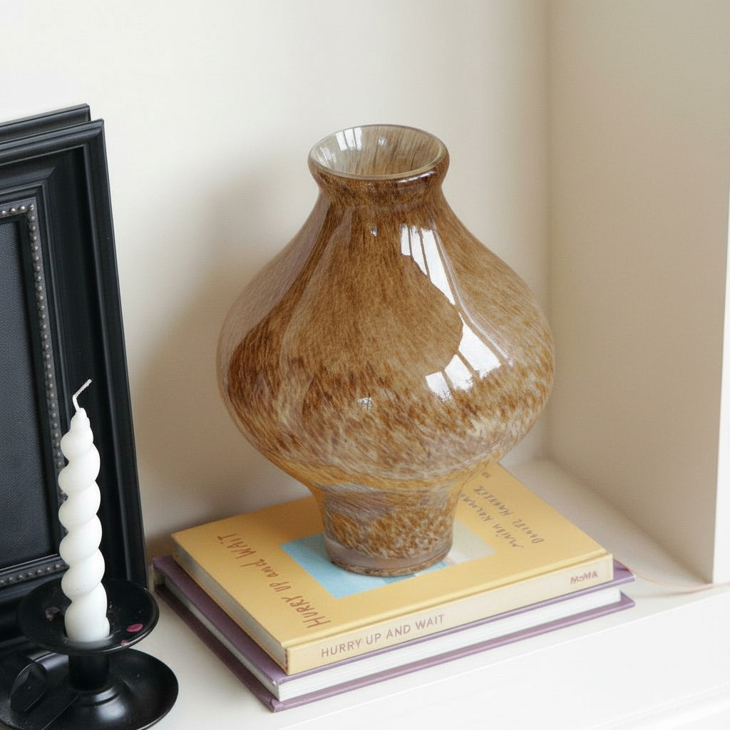 Side view of speckled amber glass vase on books
