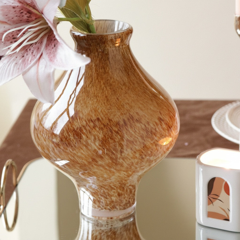 Speckled amber glass vase displayed on reflective tray