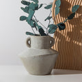 Speckled beige ceramic vase with two handles styled with eucalyptus leaves modern minimalist decor