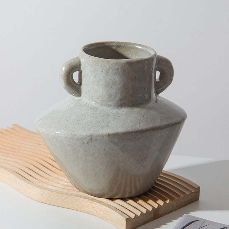 Angled view of geometric ceramic vase on wooden wave board