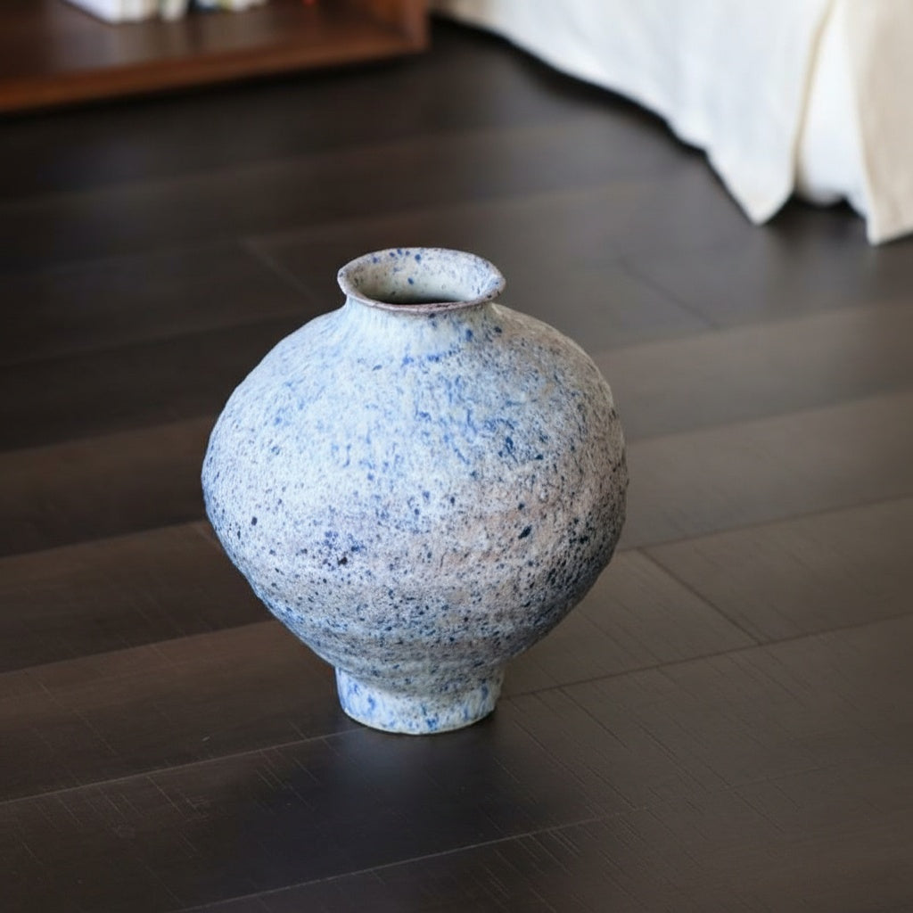 High angle view of textured blue vase on dark floor