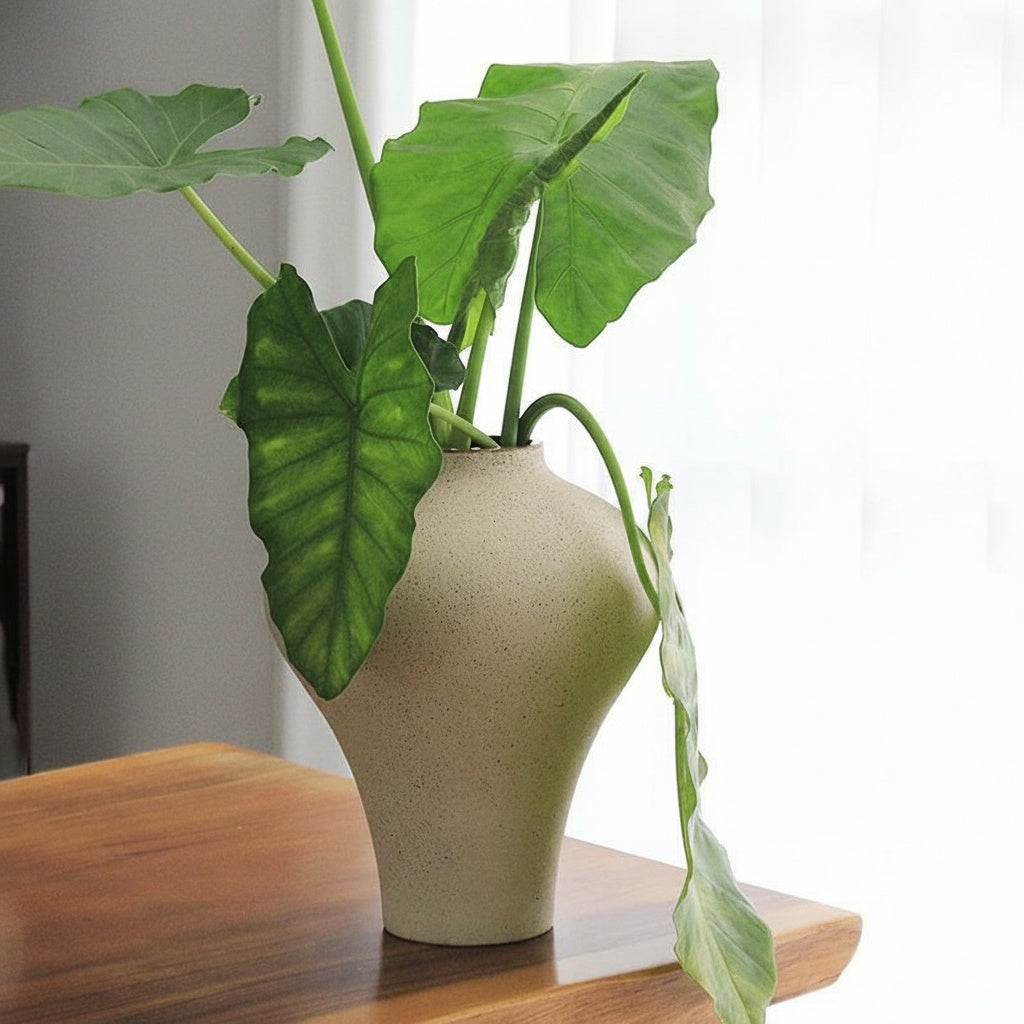 White speckled ceramic vase with green leaves on wooden surface