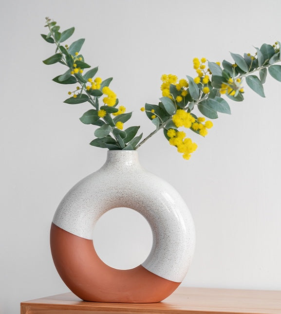 Large speckled ceramic vase with eucalyptus on wooden table
