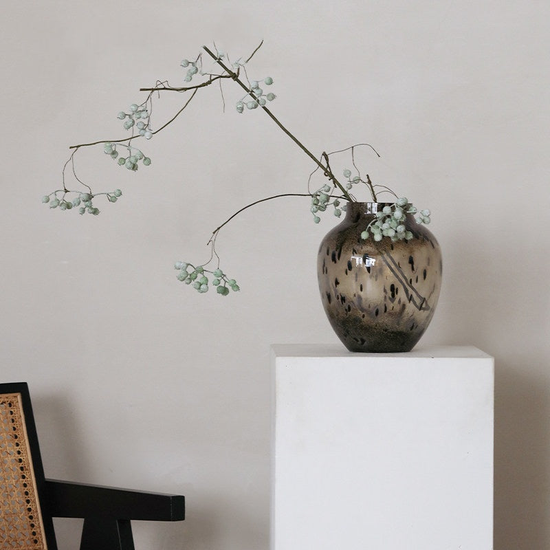 Brown glass vase with green berry branch