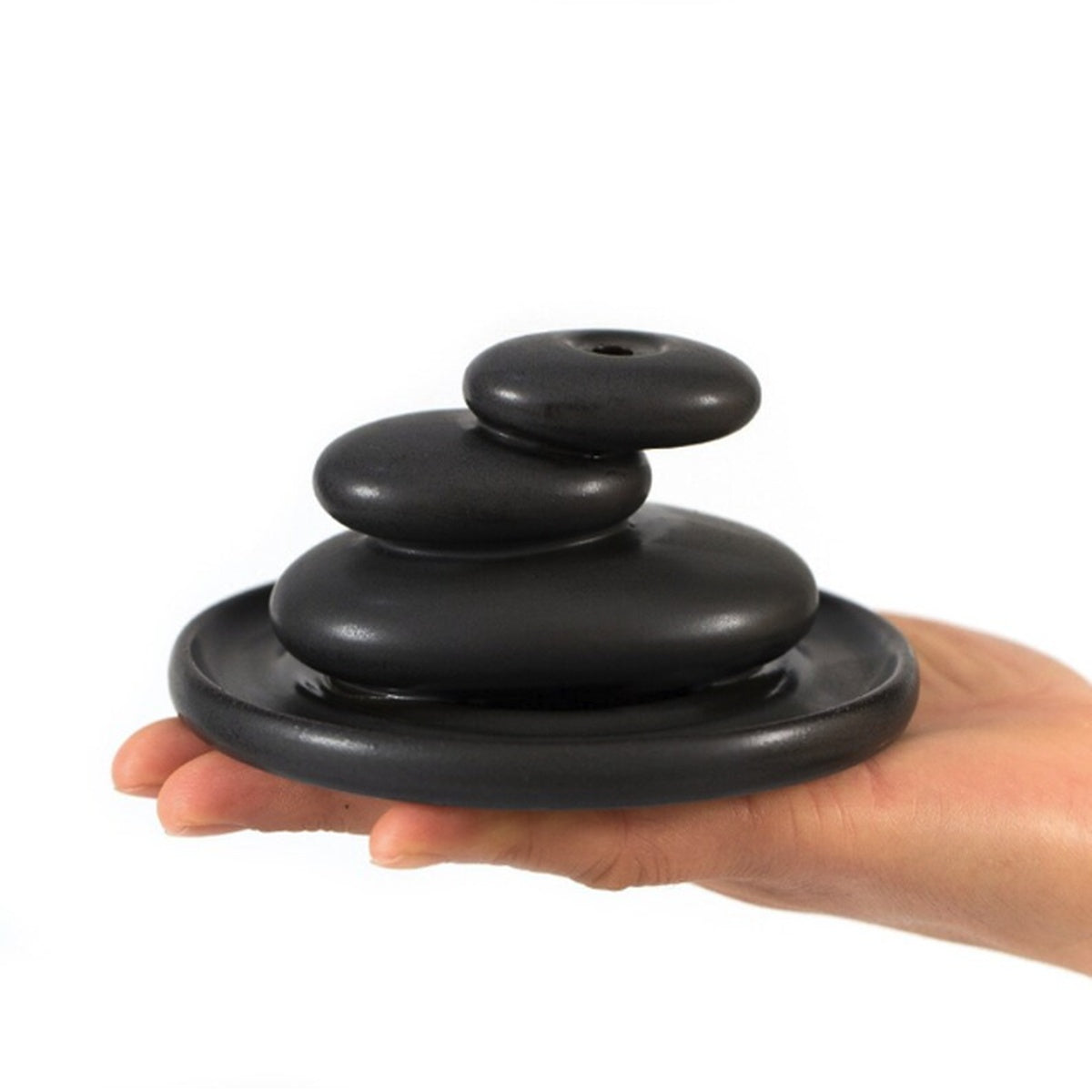 Hand holding compact black ceramic backflow incense burner for tabletop decor