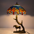 Front view of lit stained glass lamp with dragonfly pattern and horse base