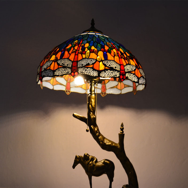 Angled view of lit dragonfly stained glass lamp showing bronze finish base