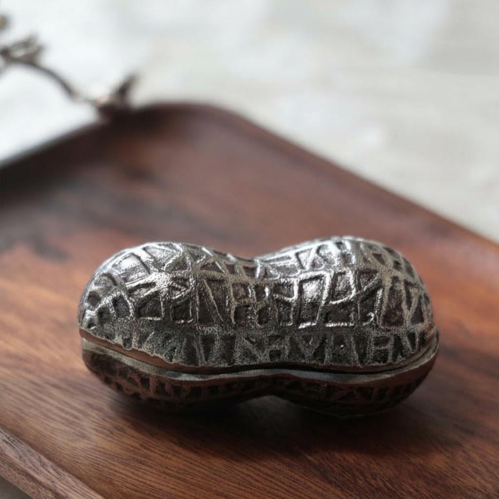 Closed stainless steel peanut shell box on wood surface