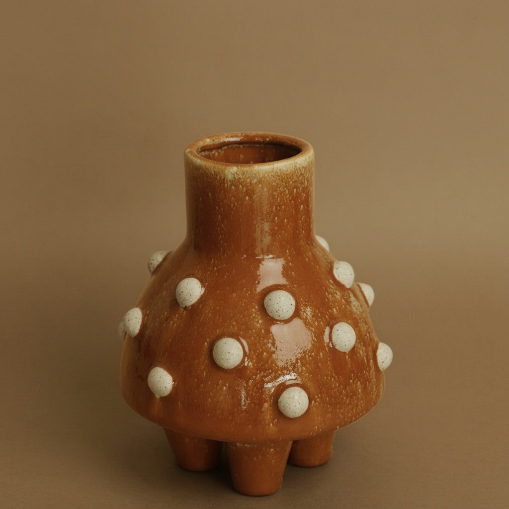 Angled view of studded ceramic vase showing tripod feet