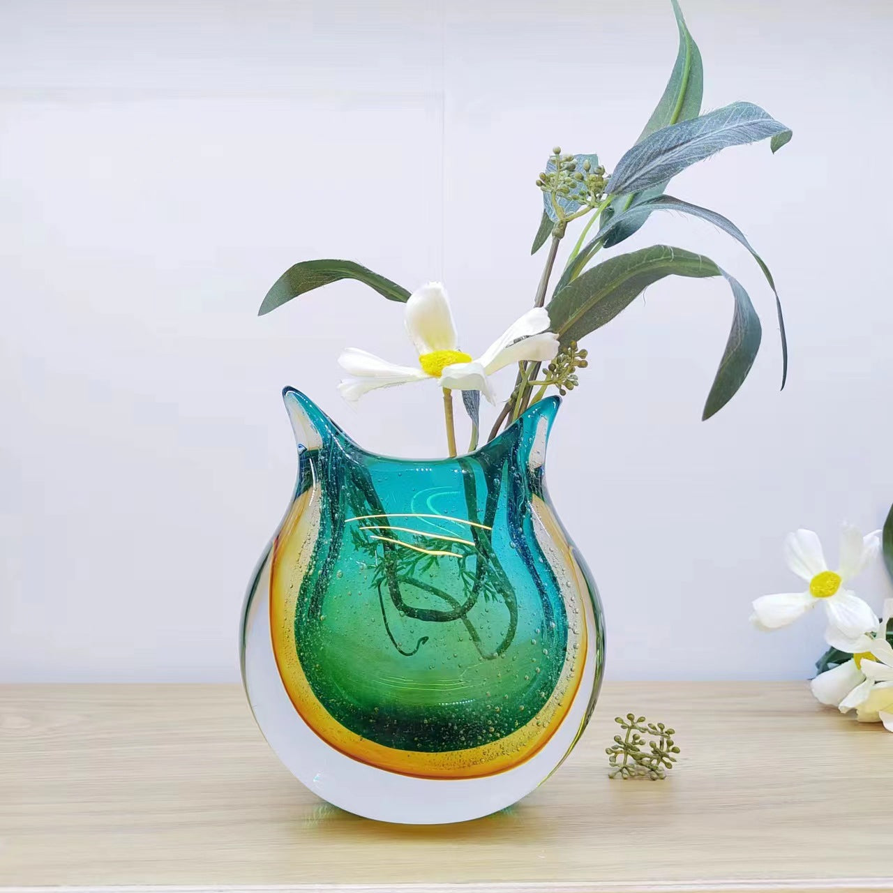 Teal and amber glass vase styled with white flowers