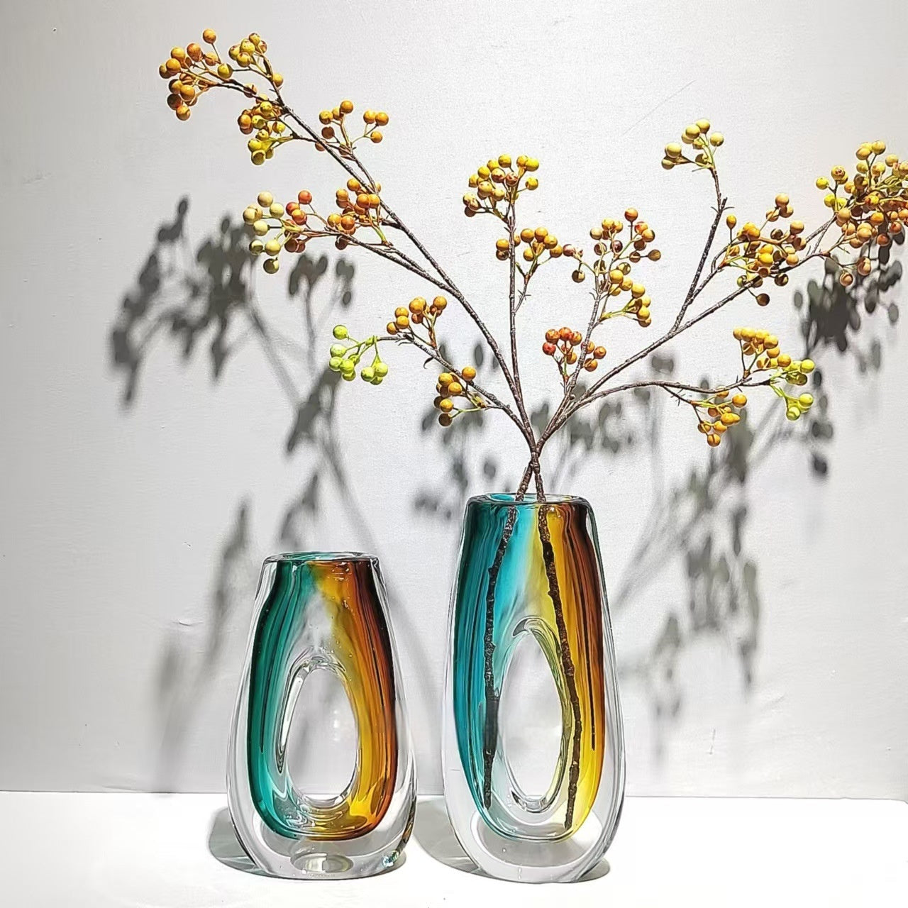 Teal and amber art glass vases with floral arrangement