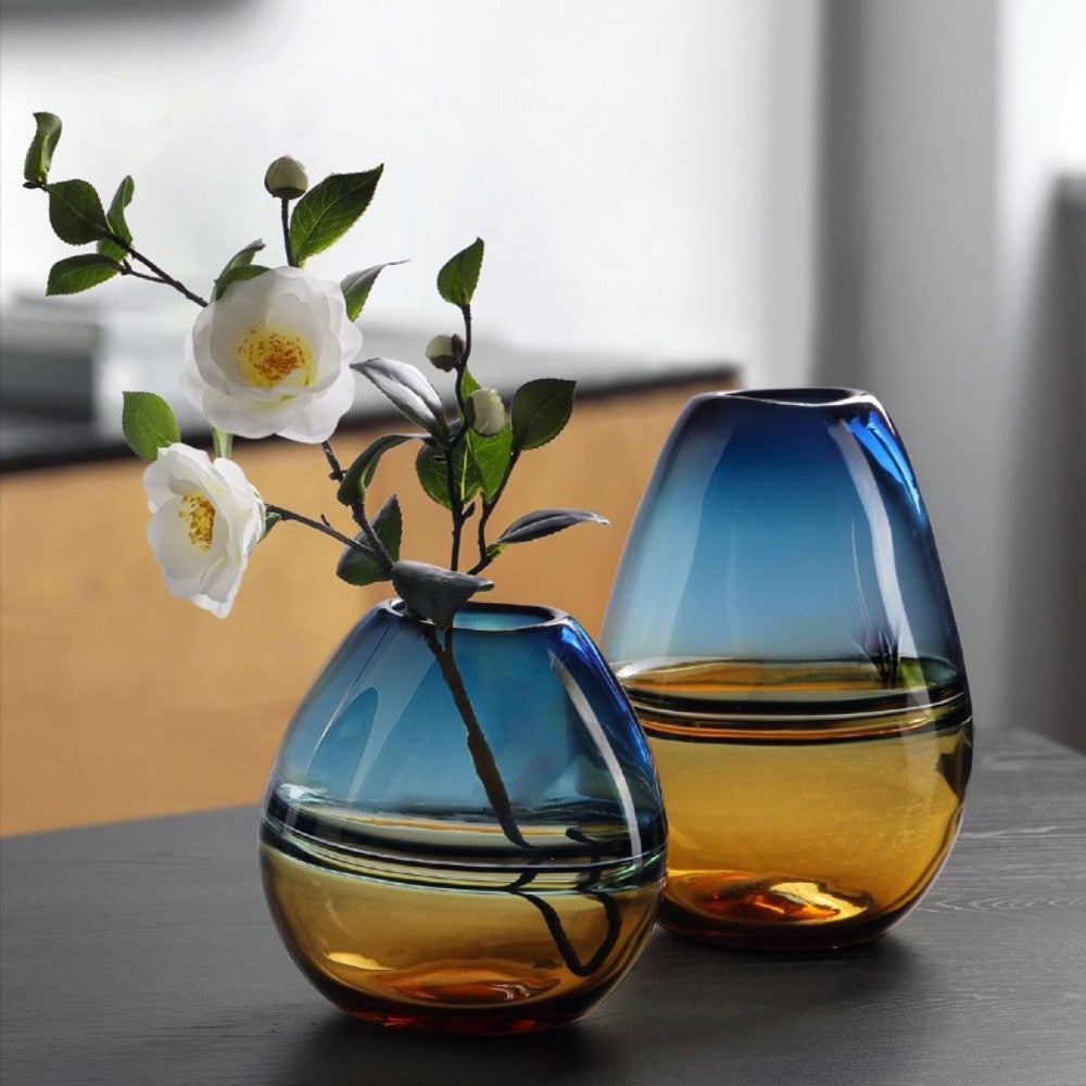 Tall and short colored glass vases with blue teal tops and warm amber bases