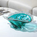 Teal art glass bowl with waved rim on white table
