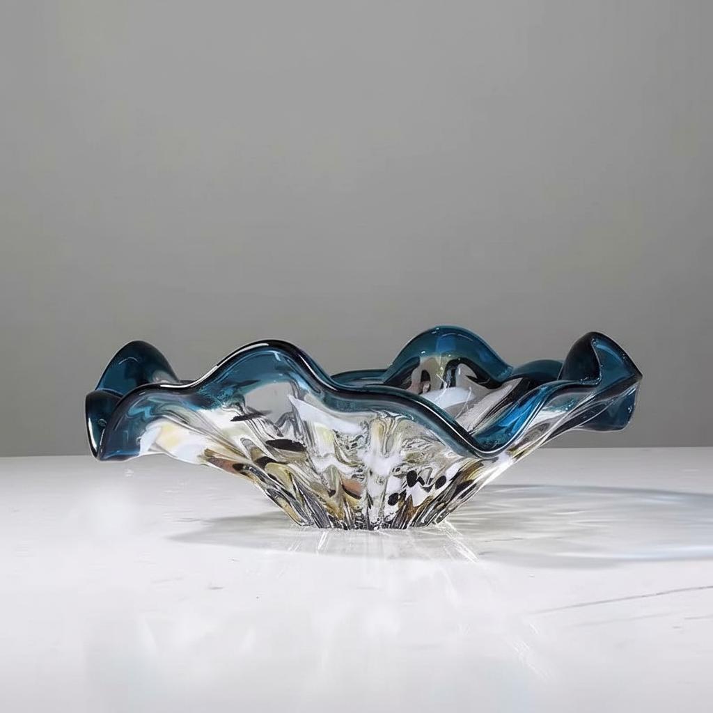 Side view of teal and clear wavy glass bowl on white surface