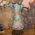 Front view of teal ceramic pitcher vase with floral and bird motifs