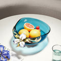 Teal glass fruit bowl with enamel flower accent filled with fruit
