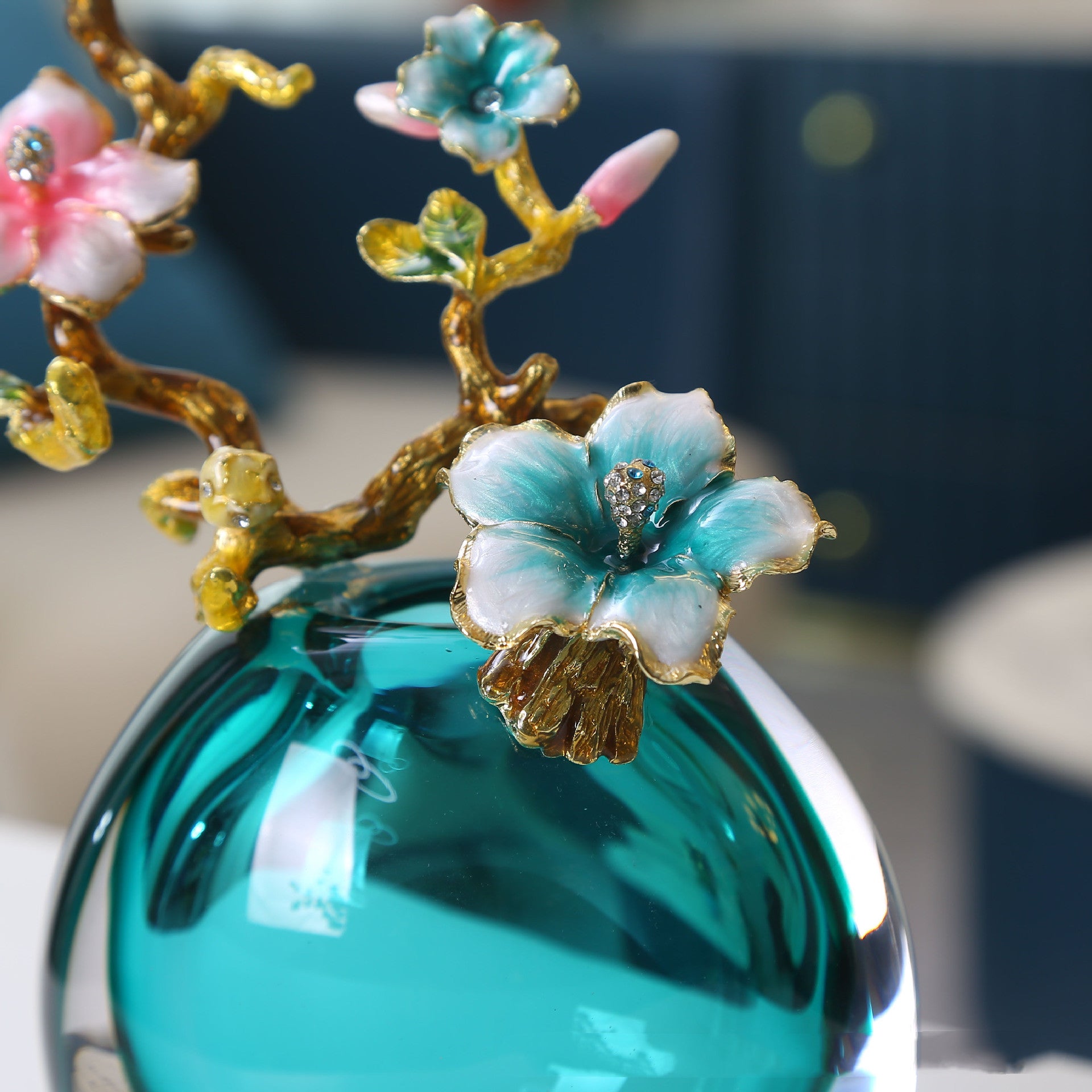 Close up of enamel flowers and crystal accents on teal vase