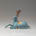 Side view of teal brass deer figurine with gold saddle