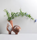 Two terracotta vases with white brushstroke accent and green foliage