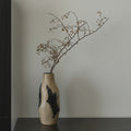 Textured beige and black organic glass vase with dried branches
